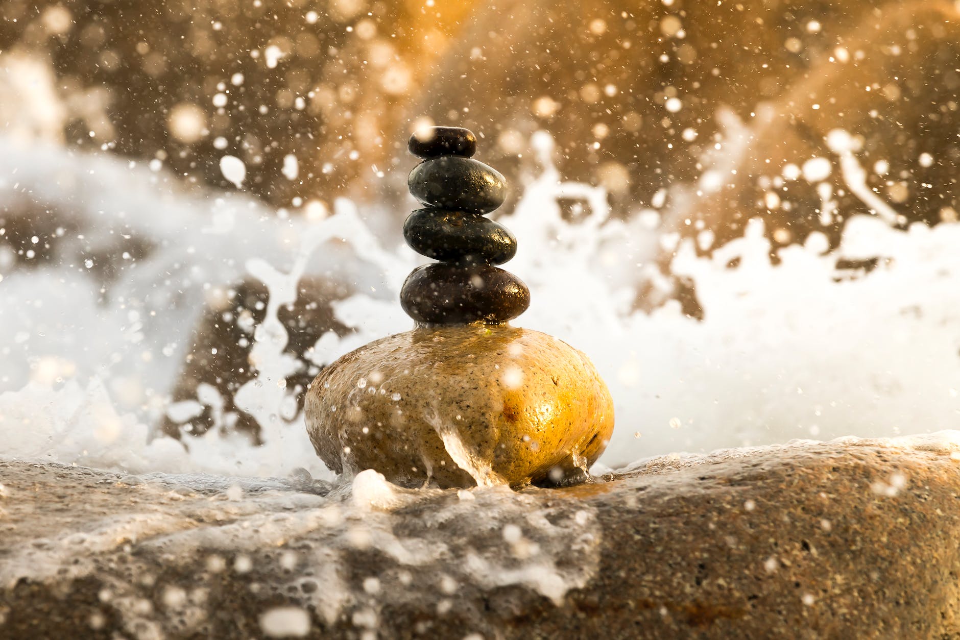 pebbles stacked in a column against a background of crashing waves