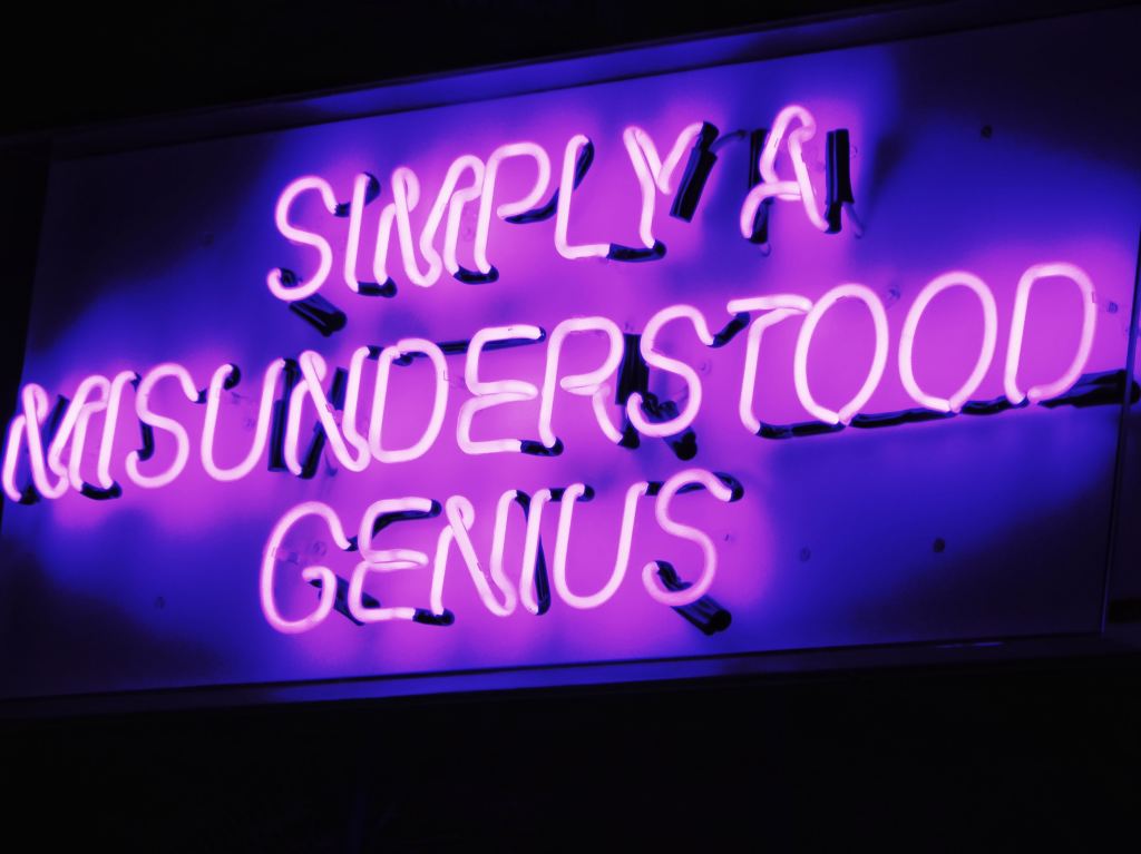 a neon sign that says: simply a misunderstood genius