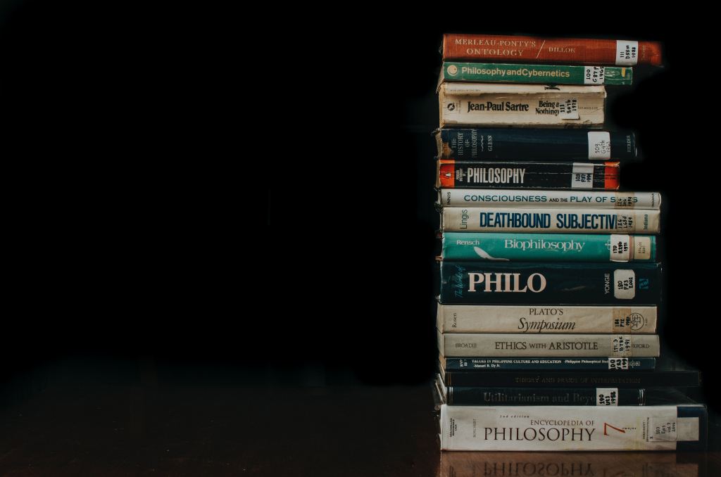 used philosophy books stacked on top of each other on a dark background