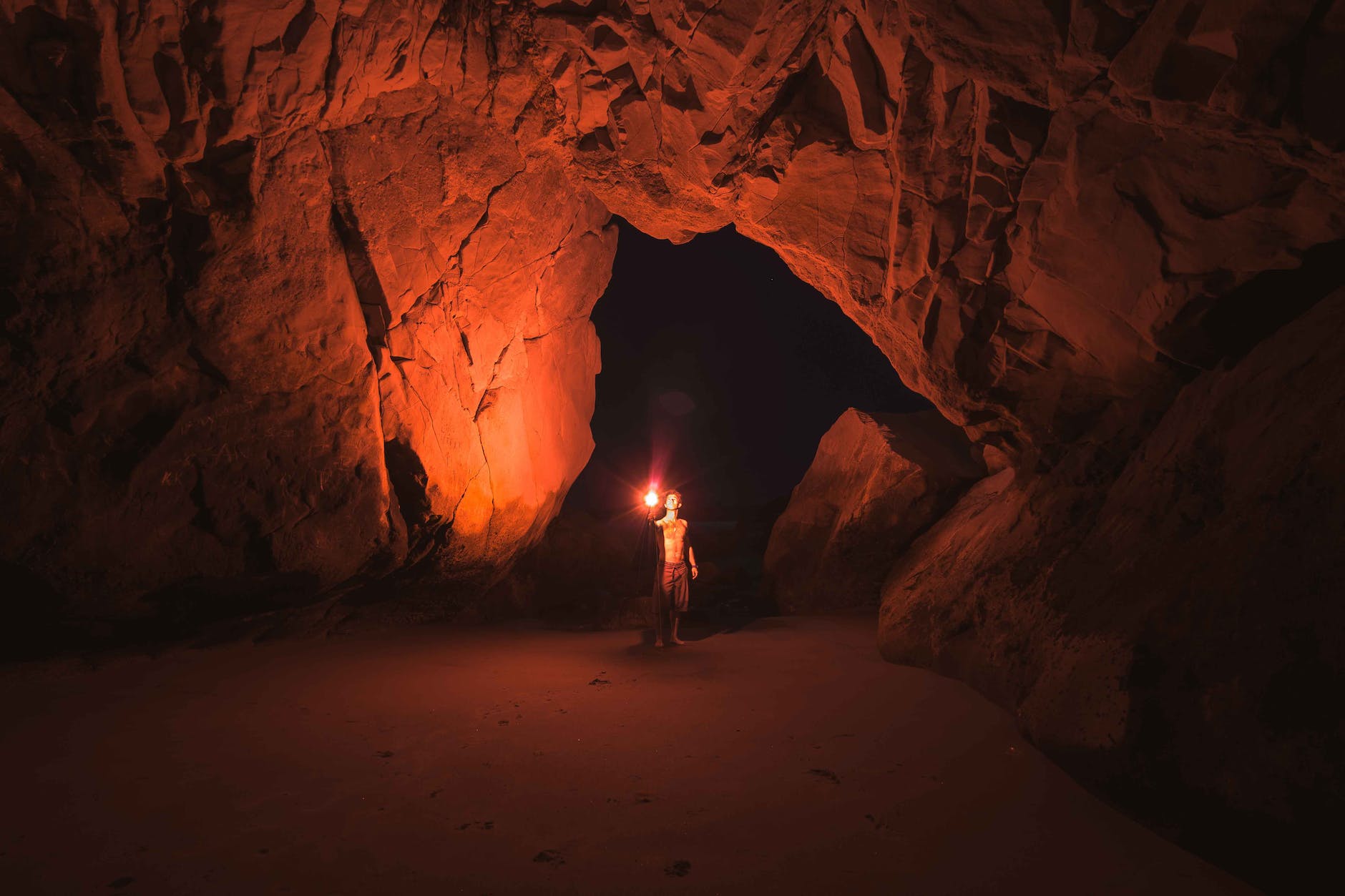 a person in a dark cave holding a red light and looking at the ceiling