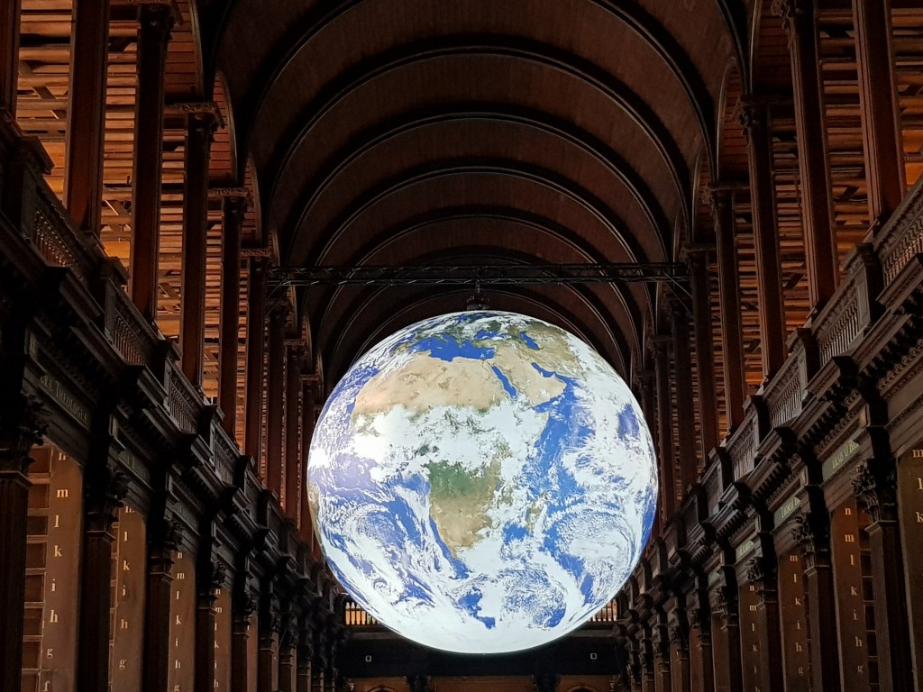 artwork of a 3d model of planet earth suspended in an old library room 