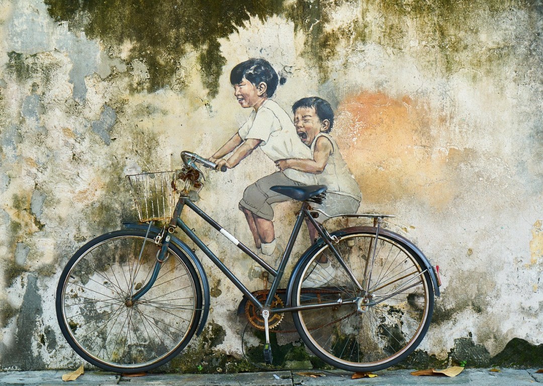street art of two children riding a bicycle